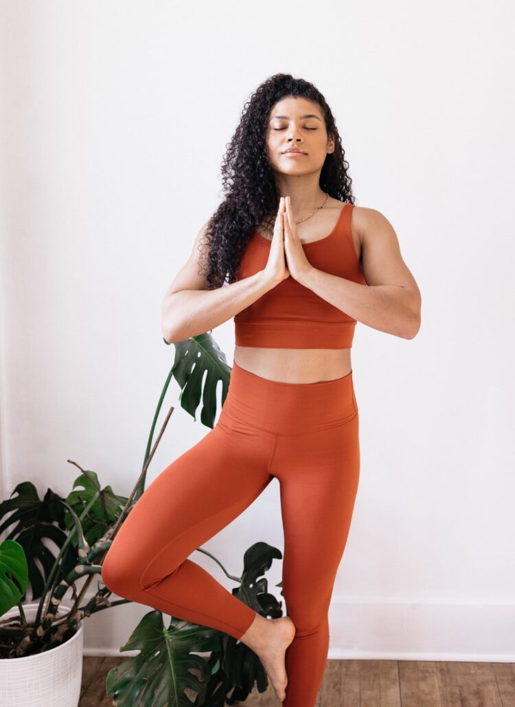 woman in yoga pose called tree pose with her hands in prayer position