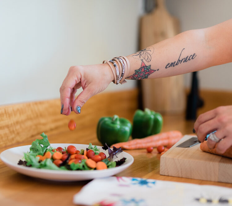 a tattooed arm shown assembling a salad