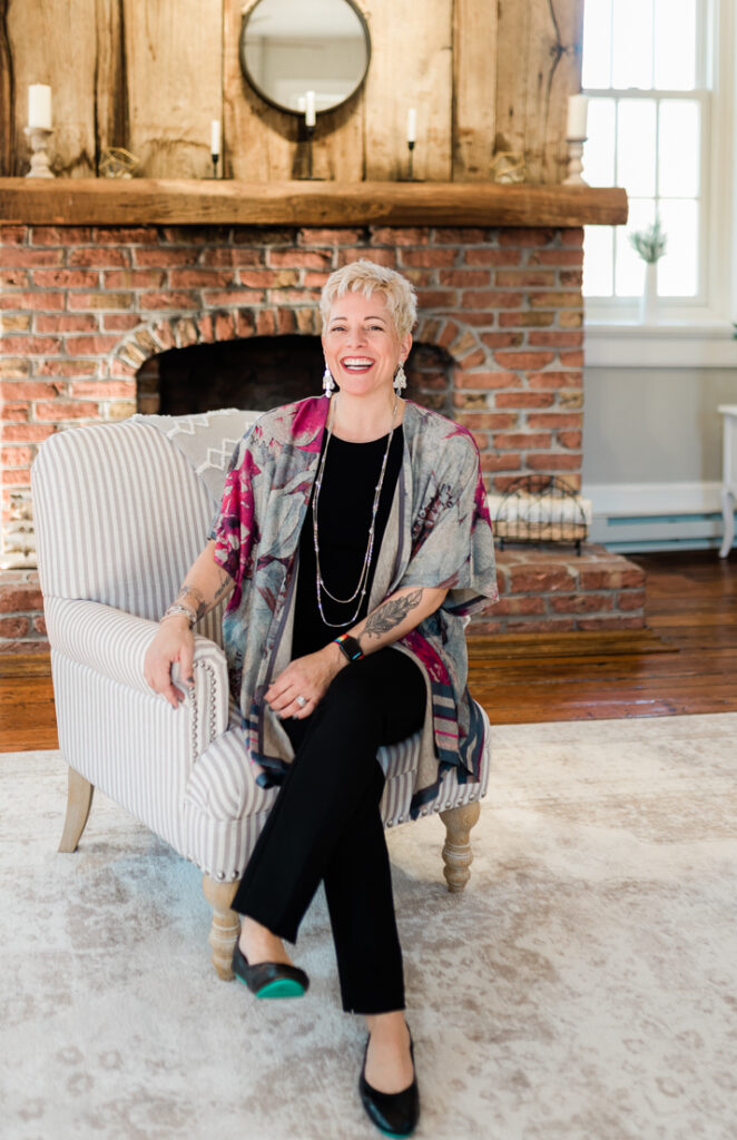 a woman sitting in a chair in a living room smiling into the camera.