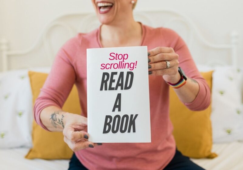 a short haired blonde woman holding a book in front of her that says "stop scrolling! Read a book"