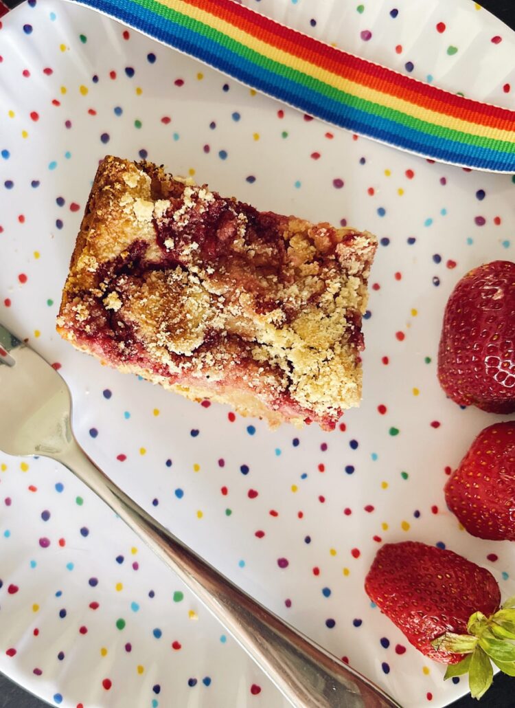 oatmeal strawberry bars on a colorful plate with a fork and additional ripe strawberries