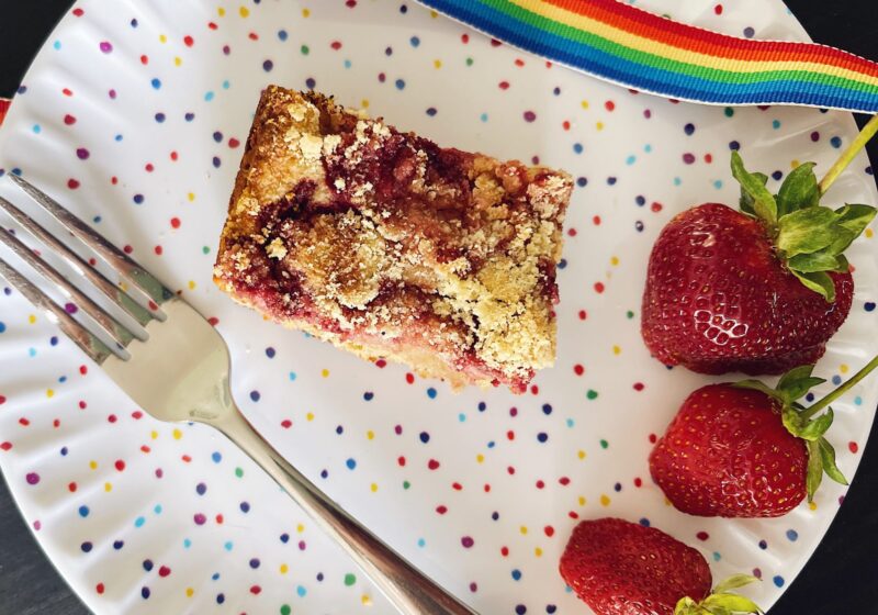 oatmeal strawberry bars on a colorful plate with a fork and additional ripe strawberries