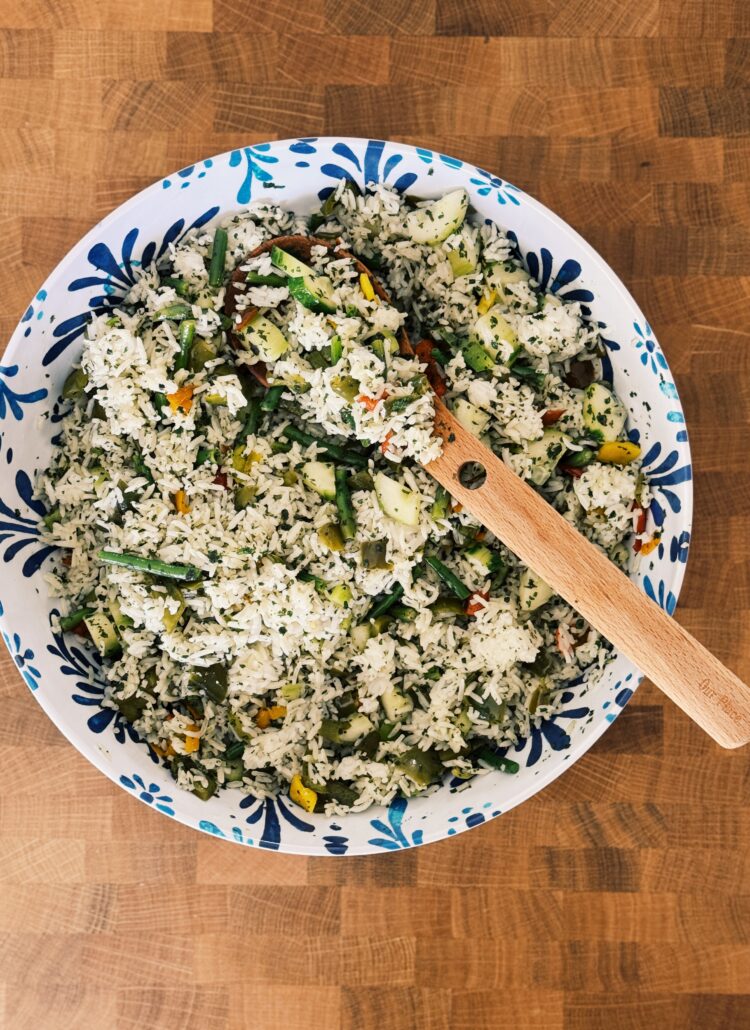 a blue and white bowl on a wooden table, the bowl is filled with the rice dish that the blog post is about. It looks fresh and yummy!