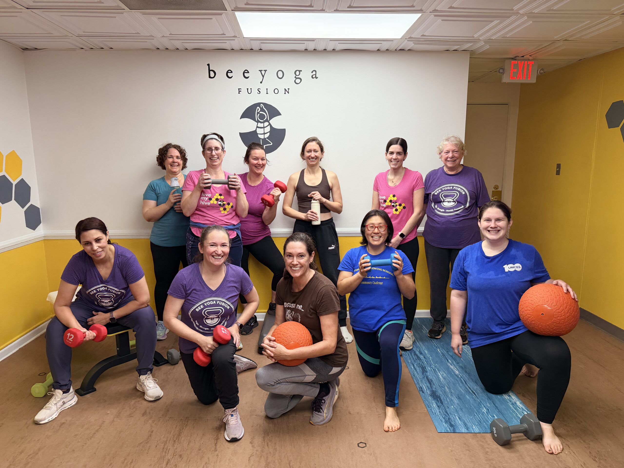 small group personal training class, a group of middle age and over women after a sweaty workout smiling while holding workout equipment.