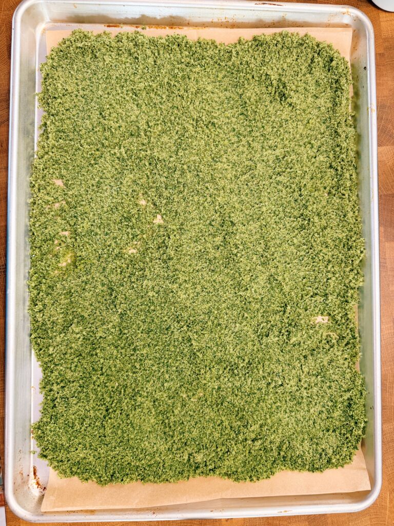 basil and salt spread on a baking sheet with parchment paper before going into the oven