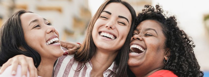 three women in an embrace laughing and smiling